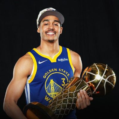 Jordan Poole holding the NBA championship trophy after winning the 2021-22 NBA season. 